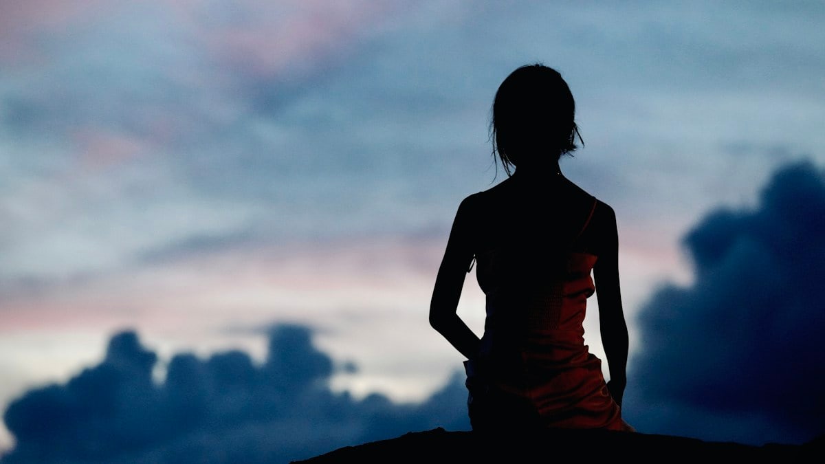 A silhouette of a woman standing on a hill